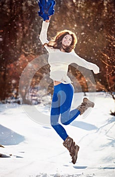 Attractive brunette girl with white sweater posing playing in winter scenery. Beautiful young woman with long hair enjoying snow