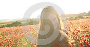 Attractive brunette lady circling and having fun in the middle of a poppy field. Video of young charming woman in a red