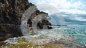 Attractive brunette sitting on a rock on the shores of the Adriatic sea , island of Vis in Croatia. Cloudy summer day, beautiful