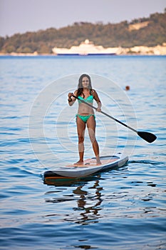 Attractive brunette on a stand up paddle board