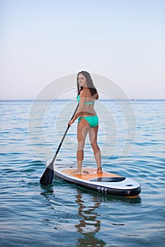 Attractive brunette on a stand up paddle board