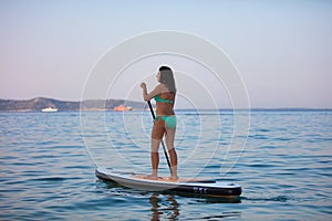 Attractive brunette on a stand up paddle board