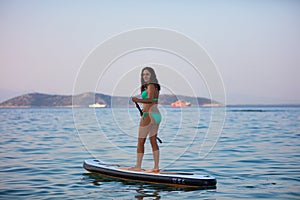 Attractive brunette on a stand up paddle board