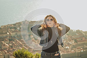 Attractive brunette with sunglasses playing with her hair as the sun set above the city of Dubrovnik in the background. Portrait