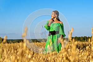 Attractive brunette woman in wheat field in green dress