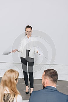 attractive business coach standing on stage and gesturing during training