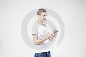Attractive business man model in white t-shirt isolated on white calling by mobile phone, push buttons hand touching screen