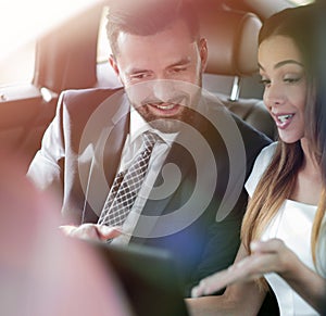 Smiling business people working in backseat of car