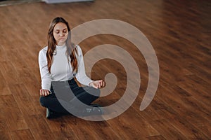 Attractive business-style girl sits on the floor in a lotus position. yoga in the office, relaxation at work. search for harmony