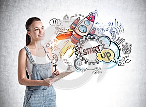 Attractive business woman in denim overalls holding a planner and dreaming about start up. Concept of success and new business