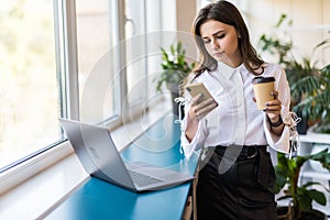 Attractive business woman drinking coffee in her office. Pretty young business woman having coffee at her workplace. Female