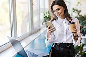 Attractive business woman drinking coffee in her office. Pretty young business woman having coffee at her workplace. Female