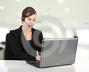 Attractive business woman with headset working on a laptop