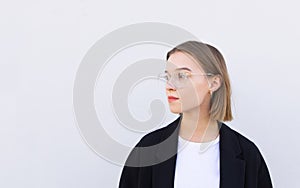 Attractive business woman in a jacket and glasses looks at the copyspace side, isolated on a white background