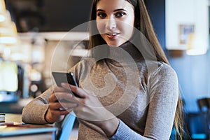 Attractive business woman sits at table in front of laptop and talks on mobile phone, negotiates on the phone.