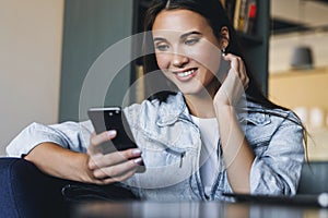 Attractive business woman sits at table in front of laptop and talks on mobile phone, negotiates on the phone.