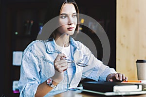 Attractive business woman is sitting at table in front of laptop. Beautiful brunette woman, holds glasses