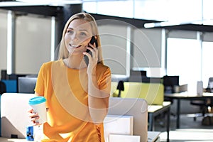 Attractive business woman talking with collegues on the mobile phone while sitting on the office desk