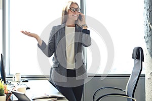 Attractive business woman talking with collegues on the mobile phone while standing in the office