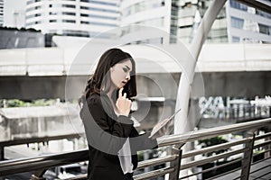 Attractive business woman using a digital tablet while standing in front of office