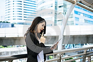 Attractive business woman using a digital tablet while standing in front of office