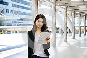 Attractive business woman using a digital tablet while standing in front of office