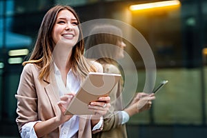 Attractive business woman using a digital tablet while standing in front of windows in an office