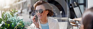 Attractive business woman in white suit sitting in cafe and talking phone