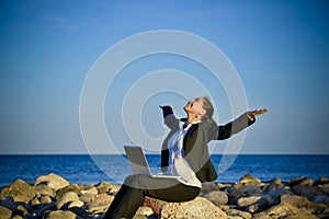 Attractive business woman working on laptop at beach