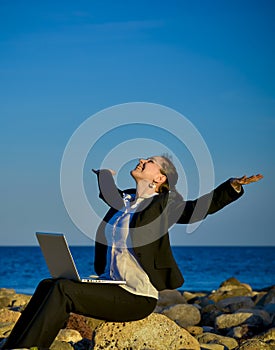 Attractive business woman working on laptop at beach