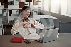 Attractive business woman working laptop while sitting in cozy cafe and showing sign love