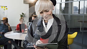 Attractive business woman working on the tablet with group of young business people on the background.