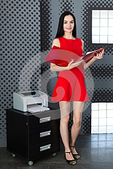 Attractive businesslady in red dress and glasses stand near the
