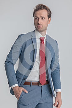 Attractive businessman in blue suit holding hand in pocket and looking to side