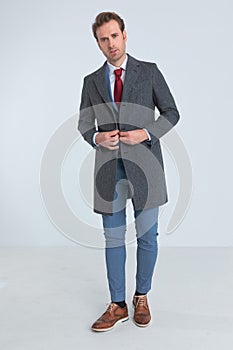 Attractive businessman closing his coat and looking at the camera