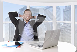 Attractive businessman happy at work smiling relaxed at computer business district office