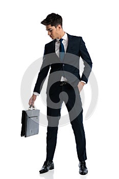 attractive businessman in navy blue suit looking down at his suitcase