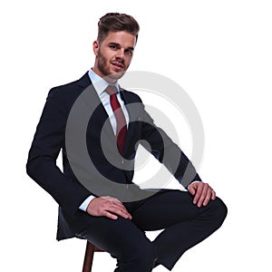 Attractive businessman in navy suit resting on wooden chair