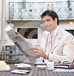 Attractive businessman reading paper in cafe.