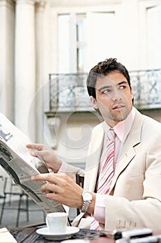 Attractive businessman reading paper in cafe.