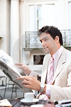 Attractive businessman reading paper in cafe.