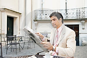 Attractive businessman reading paper in cafe.