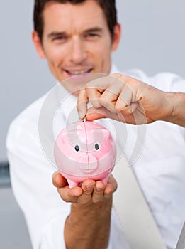 Attractive businessman saving money in a piggybank