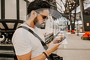 Attractive businessman sending message on his mobile phone.Casual professional entrepreneur using smartphone at hall of