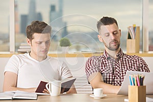 Attractive businessmen reading book and doing paperwork