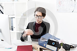 Attractive businesswoman checking time at wristwatch