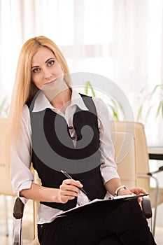 Attractive businesswoman with clipboard sitting in the office