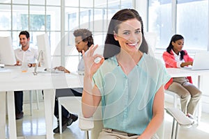 Attractive businesswoman giving OK sign to camera
