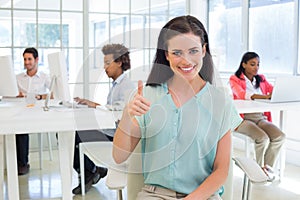 Attractive businesswoman giving thubms up to camera