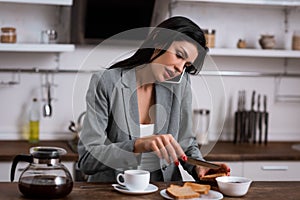 Attractive businesswoman holding knife near toast